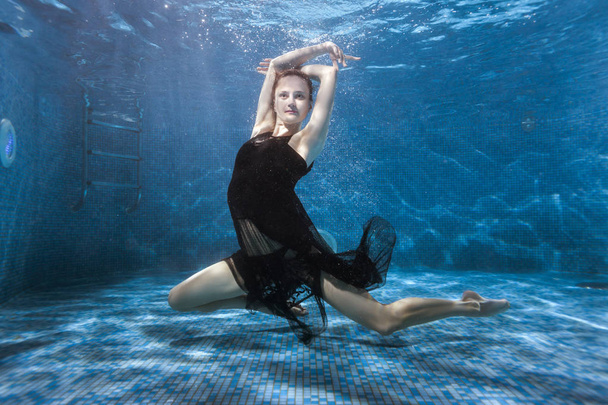 Nainen tanssii veden alla altaassa.
. - Valokuva, kuva