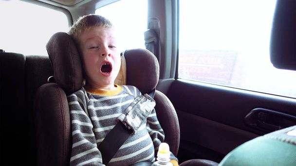 Garçon mignon dans un siège auto enfant regarde par la fenêtre
 - Photo, image