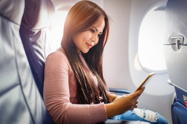 Azjatyckie kobiety użyć telefonu komórkowego wewnątrz samolotu - Zdjęcie, obraz