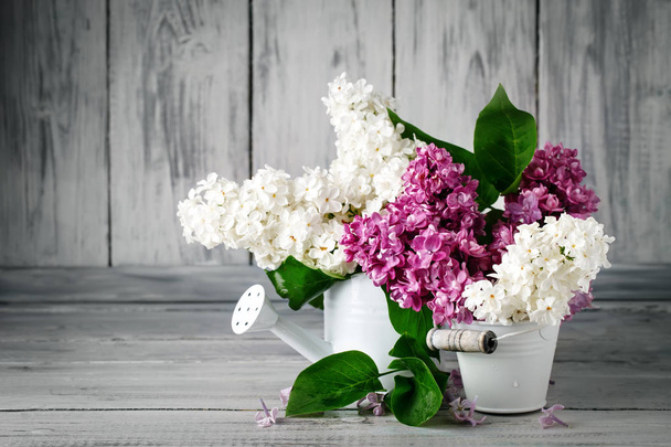 Branches are colored lilac in a basket on the background of wooden boards. - Foto, imagen