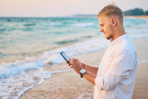 Ember használ smartphone, a tenger partján - Fotó, kép