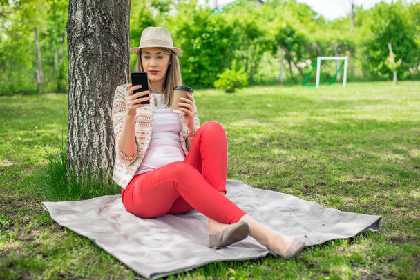 Woman relaxing at the park and using smart phone. - Zdjęcie, obraz