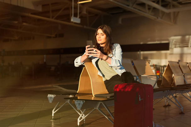 Женщина переписывается и пользуется телефоном перед посадкой в самолет
 - Фото, изображение