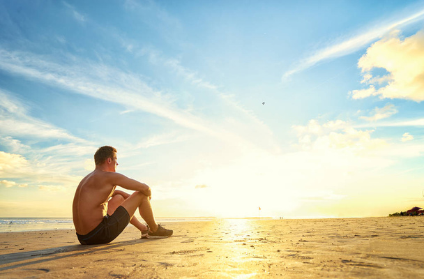 Muscular man sitting on beach  - Foto, Imagen