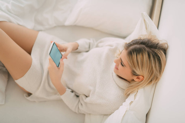 mujer relajante en la cama con smartphone
 - Foto, Imagen