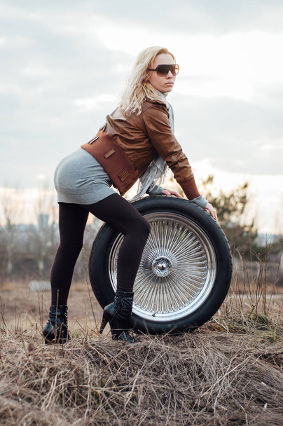 Sexy young girl sits on a large wheel - Foto, imagen