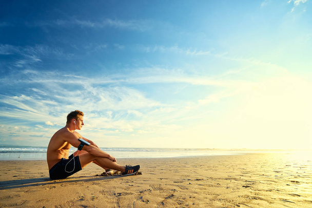 Man with smartphone sitting on beach - Foto, afbeelding