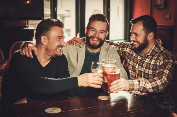 Веселые старые друзья веселятся и пьют пиво в пабе
. - Фото, изображение