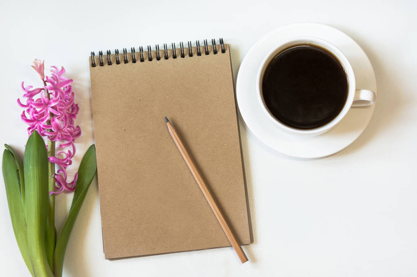 Workspace for blogger with notebook of craft paper, pencil, cup of coffee, flower on white background. Image with copy space for your text. - Valokuva, kuva