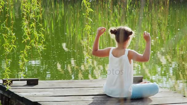 Chica joven relajándose meditando en el lago
 - Imágenes, Vídeo