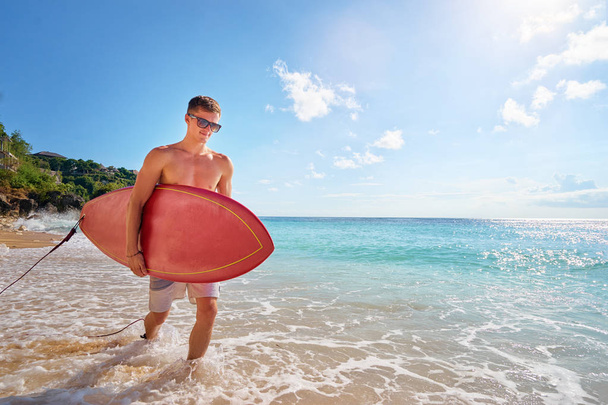 Young man carrying surf board - Фото, зображення