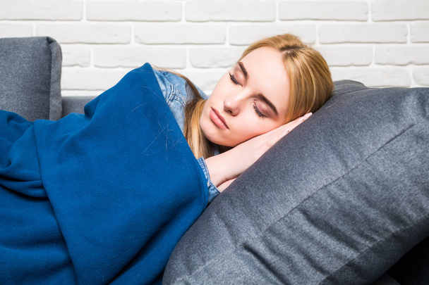 Krásná blonďatá žena na gauči zabalený do modré deky - Fotografie, Obrázek