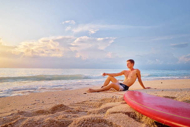 Man sitting with surf board - Фото, зображення