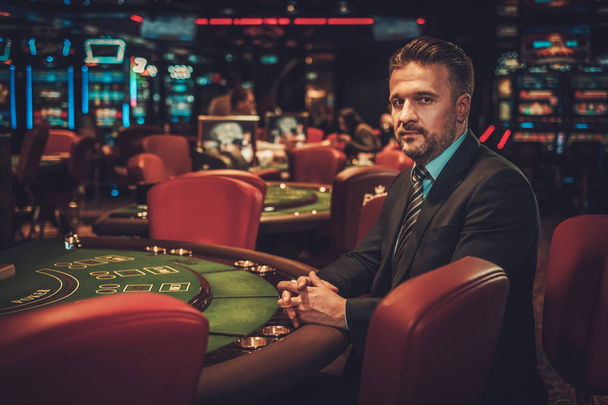 Hombre de clase alta detrás de la mesa de juego en un casino
 - Foto, imagen