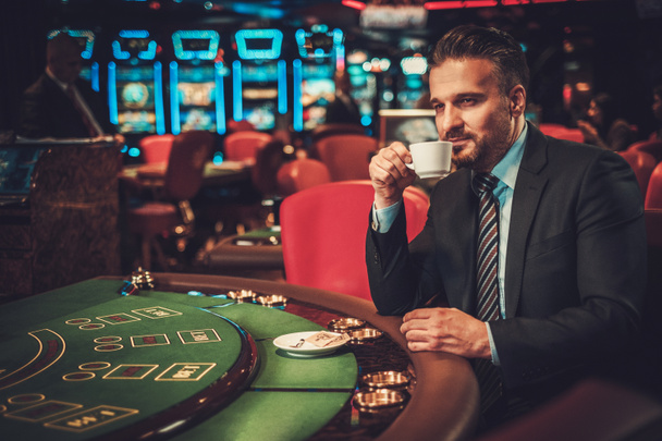 テーブルのカジノでギャンブルの背後にある上流階級の男 - 写真・画像