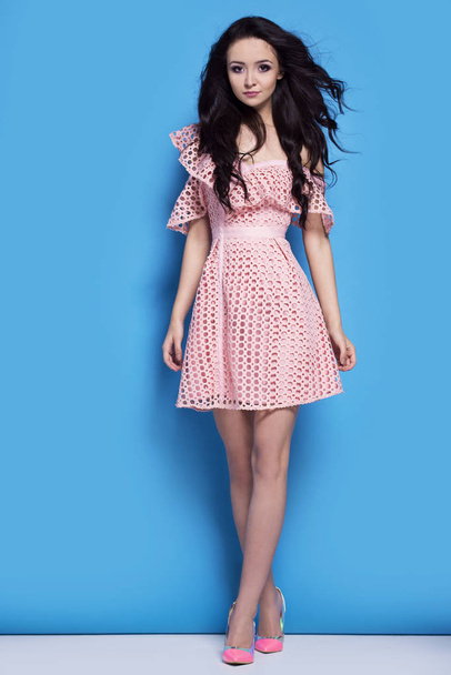 Beautiful woman in pink dress on blue background - Photo, Image