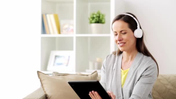 happy woman with tablet pc and headphones at home - Záběry, video