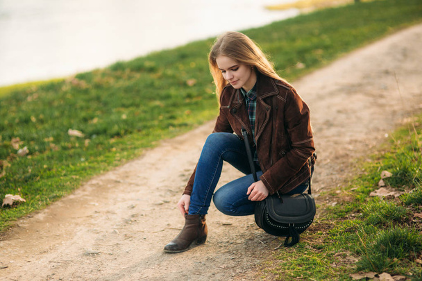 Egy gyönyörű lány sétál végig a rakparton. Szőke haj, barna kabátot. Tavaszi. - Fotó, kép