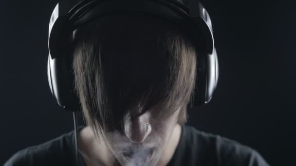 Fiatal ember hallgat zenét a fejhallgatót és a dohányzás elektronikus cigaretta - Felvétel, videó