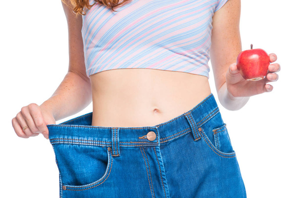 Menina fina em jeans velhos com uma maçã na mão em uma parte traseira branca
 - Foto, Imagem