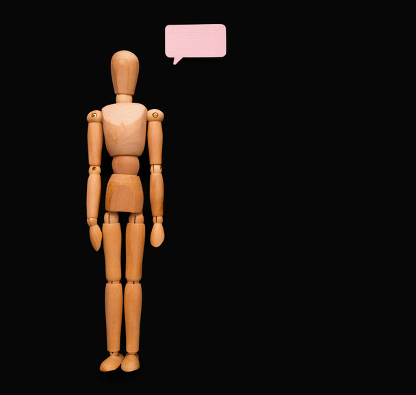 Wooden man with speech bubble, black background - Photo, Image