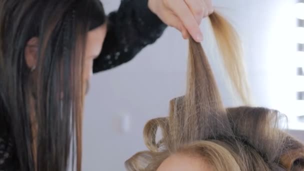 Profesjonalny salon fryzjerski robi fryzurę dla młode ładne kobiety - Dokonywanie loki - Materiał filmowy, wideo