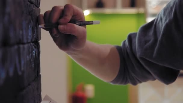 Закрыть Молодая художница переносит графический дизайн на стену черного кирпича в кофейне с помощью проектора
 - Кадры, видео