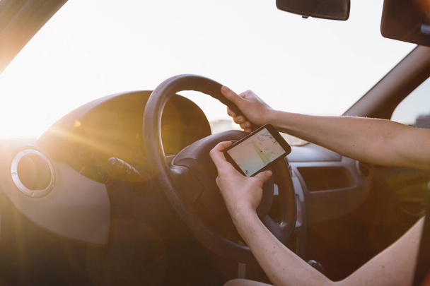 Jeune conductrice utilisant un smartphone à écran tactile et navigation GPS dans une voiture. - Photo, image