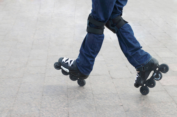 Молодий чоловік у роликових ковзанах та захисних колінах катається на колінах
  - Фото, зображення