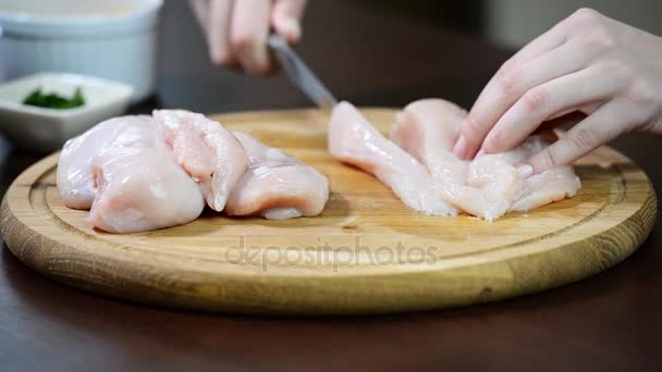 Mãos femininas cortando em fatias peito de carne de frango cru a bordo
 - Filmagem, Vídeo
