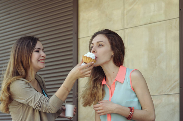 One girl feeds another while they drink coffee - Photo, Image