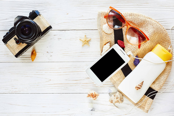 капелюх, сонцезахисні окуляри, телефон і сонцезахисний крем
 - Фото, зображення