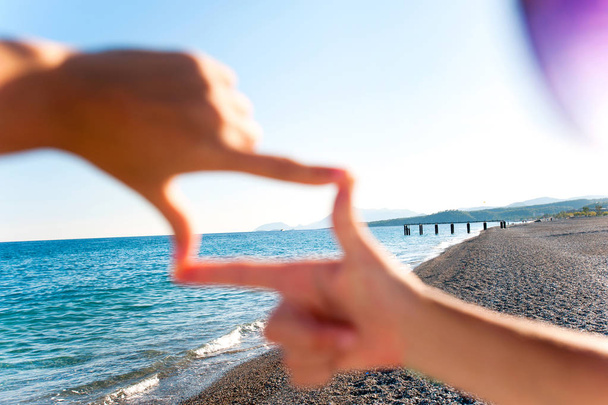 Композиція палець рамка- руки дівчини захоплюють вражаючий морський пейзаж
 - Фото, зображення