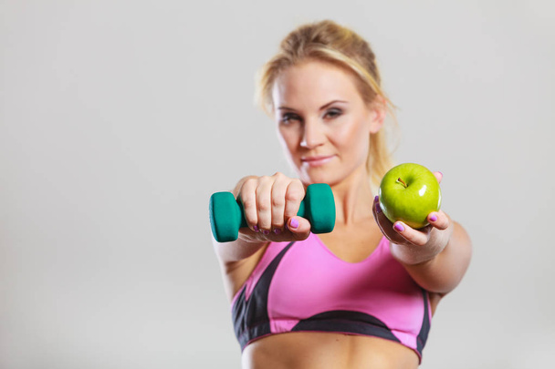 Diet fit body. Girl holds dumbbells and apple fruit - Fotografie, Obrázek