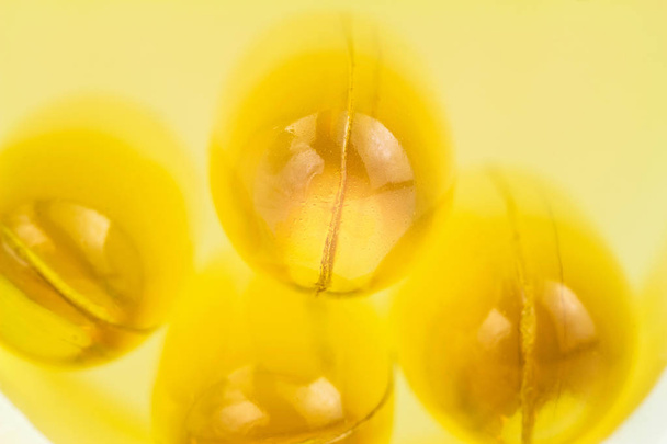 Yellow capsules omega 3, fatty acid, fish oil on heap, macro image. - Photo, Image