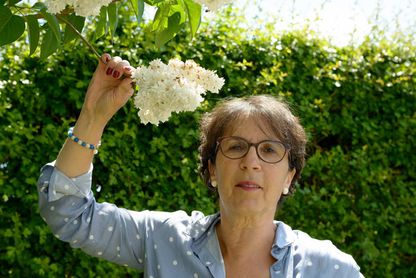mujer mayor en su jardín con flores
 - Foto, imagen