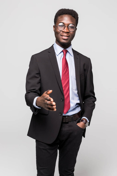 Joven empresario africano feliz sonriendo mientras da apretón de manos en gris
 - Foto, imagen