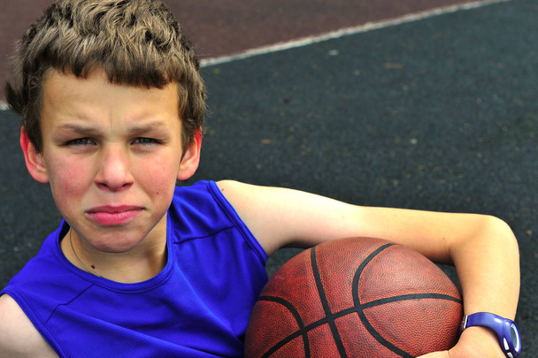 Basketbol sahasına oturan genç - Fotoğraf, Görsel