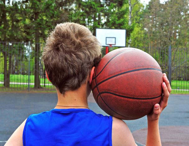 Young basketball player with a ball on his shoulder - 写真・画像