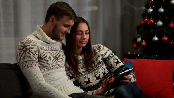 Jovem casal apaixonado sentado no sofá vermelho, usando o tablet e aproveitando o tempo juntos
. - Filmagem, Vídeo