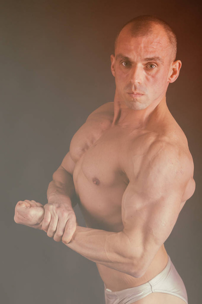 A man with a gorgeous muscular body on a black background - Fotoğraf, Görsel