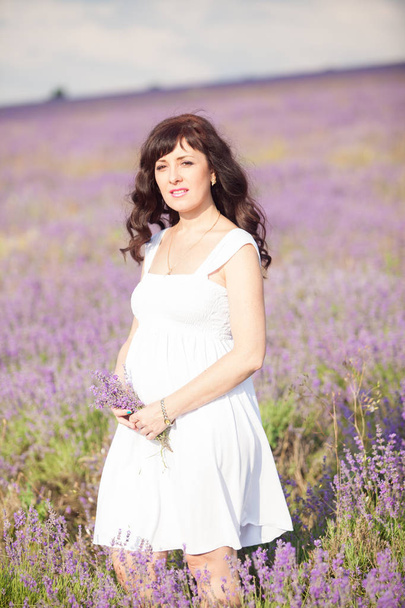a pregnant woman in a field of flowers of lavender purple - Fotografie, Obrázek