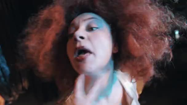 Kobieta w Bujne włosy imbir wig, wykrzywiając i tańca na scenie z zespołem - Materiał filmowy, wideo
