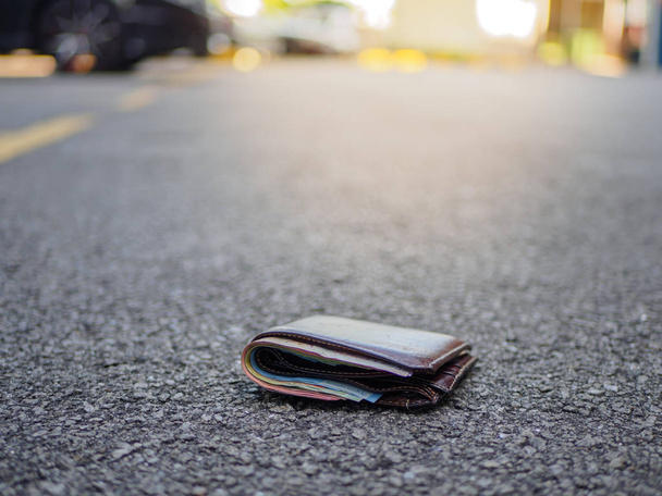 billetera con gota de dinero en la calle, concepto de dinero perdido, espacio de copia en la parte superior
 - Foto, imagen