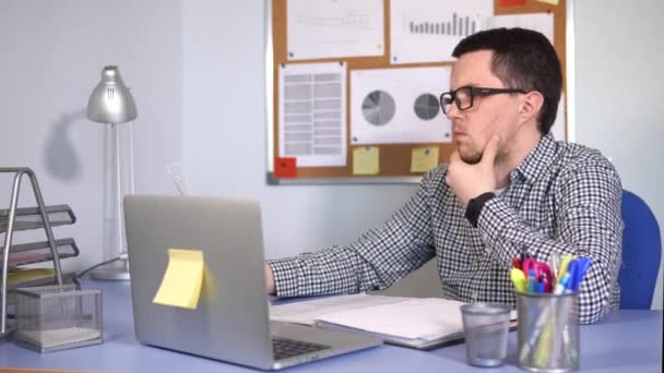 Ο προ! ιστάμενος ελέγχει τα έγγραφα που κάθεται στο γραφείο του, όπου στέκεται ο φορητός υπολογιστής - Πλάνα, βίντεο