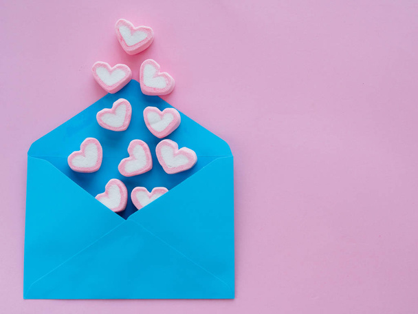 Love letter valentine's day concept. Closeup image of blue letter with copy space arranged on pink background  and colorful of hearts - Zdjęcie, obraz