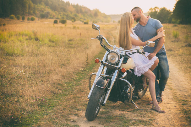 Loving couple on a motorcycle in a field - Photo, Image