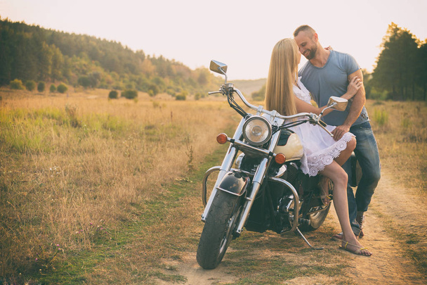 Verliefde paar op een motorfiets in een veld - Foto, afbeelding