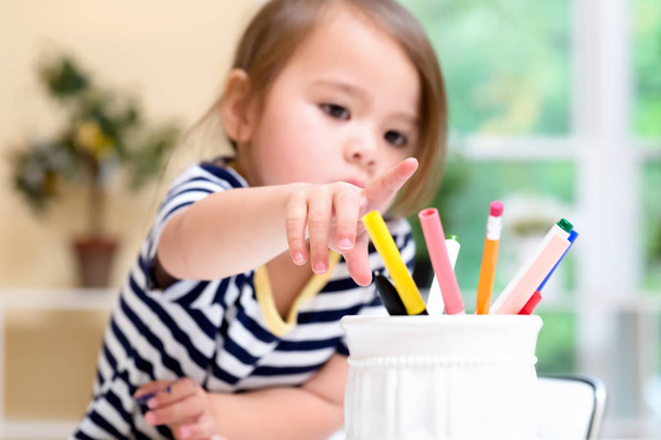 Toddler girl reaching for markers - Foto, afbeelding
