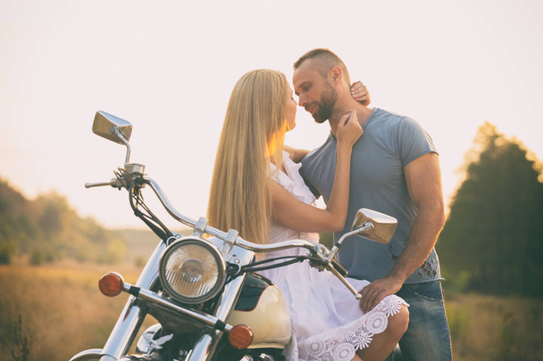 Loving couple on a motorcycle in a field - Photo, Image